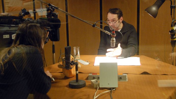 Schauspieler Boris Aljinovic am Mikrofon, er liest eine OHRENBÄR-Radiogeschichte, gefilmt vom rbb-Team der Abendschau (Quelle: rbb/OHRENBÄR/Birgit Patzelt)