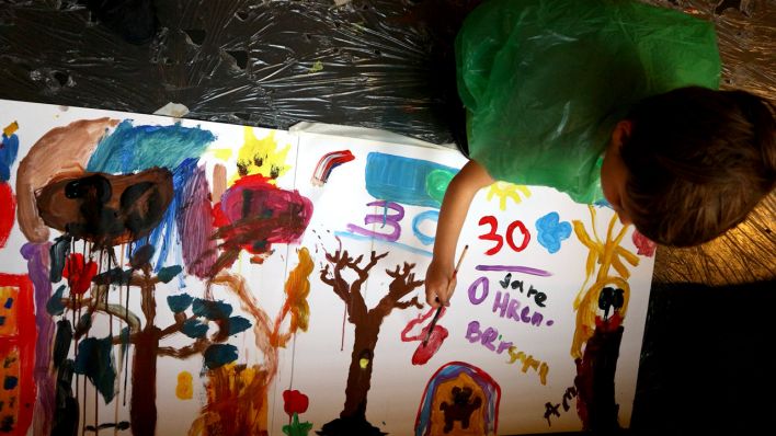 Ein Kind am Boden malt auf einem großen Blatt (Quelle: rbb/Martha Zan)