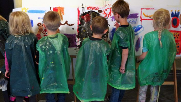 Kinder mit grünen Umhängen, an der großen Malwand (Quelle: rbb/Martha Zan)