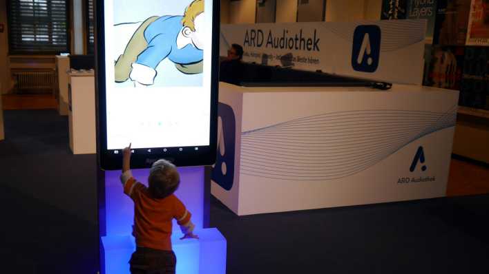 Ein kleiner Junge vor einem großen Bildschirm in Form eines Smartphones, er schaut sich "OHRENBÄR" in der ARD Audio App an (Quelle: rbb/OHRENBÄR/Sonja Kessen)