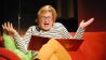 Schauspielerin Karen Matting liest mit den Armen gestikulierend vor, auf der roten Lesecouch (Quelle: rbb/OHRENBÄR)
