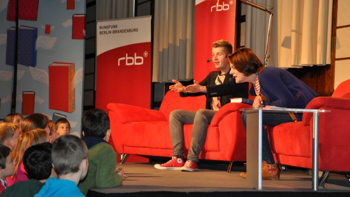 KiKA-Moderator Tim Gailus und rbb-Moderatorin Britta Elm auf der Bühne, im Gespräch mit den Kindern vor der Bühne (Quelle: rbb/Tobias Potratz)