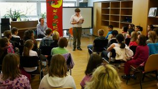 Autorin Karen Matting liest in einem Klassenzimmer, Schüler sitzen auf Stühlen davor (Quelle: rbb/Redaktion OHRENBÄR/Birgit Patzelt)