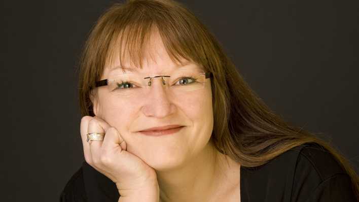 Porträt der Autorin Petra Bartoli vor einem braunen Hintergrund (Quelle: privat)