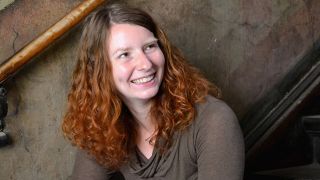 Autorin Katharina Bendixen sitzend auf einer Treppe im Hausflur (Quelle: Benjamin Gladis)