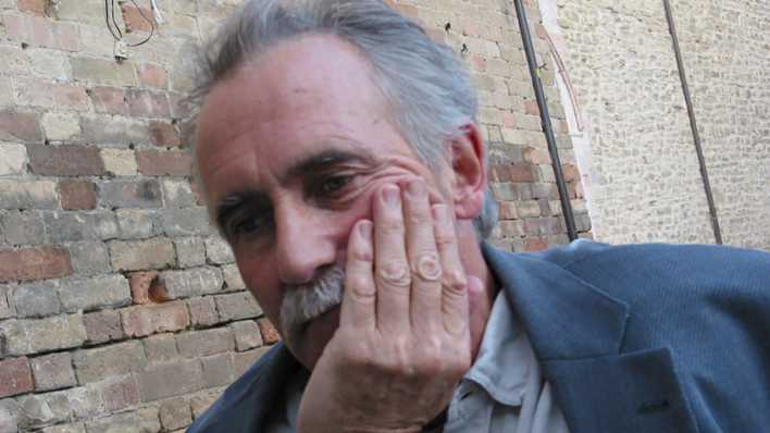 Porträt des Autors Peter Blie, Jacket locker über der Schulter, Kopf auf einer Hand gestützt, vor einer unverputzten Backsteinmauer (Quelle: privat)