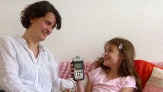 Kinder-Reporterin Hannah gemeinsam mit Illustratorin Daniela Bunge im Interview, auf der Couch, mit einem Aufnahmegerät, sie lachen (Quelle: rbb/OHRENBÄR/Alja Mai)