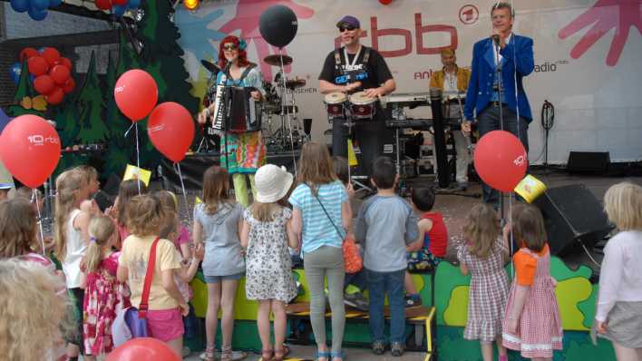 Die Band Rumpelstil auf der Bühne, davor Kinder mit roten Luftballons © rbb/Redaktion OHRENBÄR