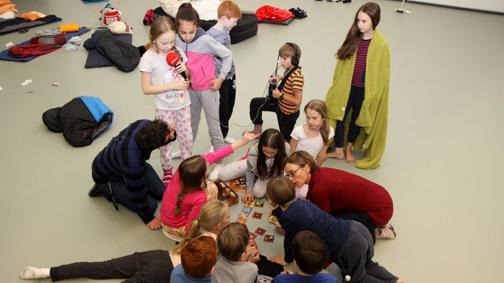 Mädchen und Jungen aus der Ballettschule mit Aufnahmegerät von radioBERLIN und Spielen, sitzen und liegen auf dem Boden (Quelle: rbb/Matthias Bartsch)