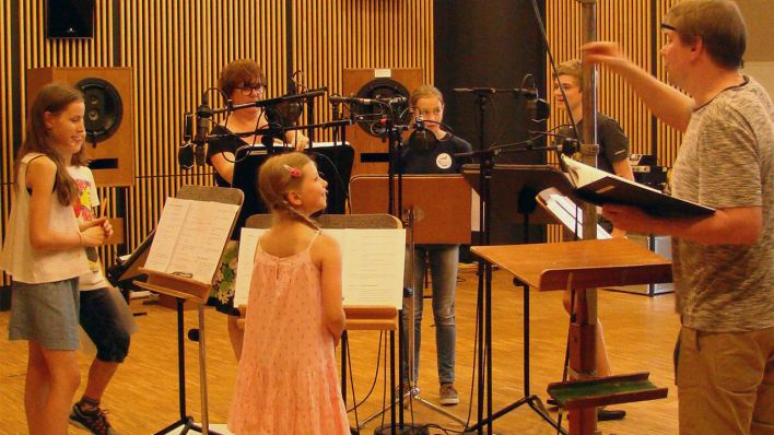 Die Kinder aus dem Hörspiel zusammen mit Regisseur Robert Schoen im Studio bei der Aufnahme (Quelle: rbb/Marie Beckmann)