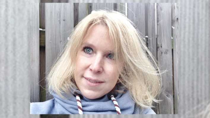 Porträt der Autorin Janine Lüttmann, vor einem grauen Lattenzaun (Quelle: privat)