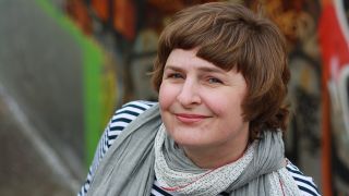 Porträt der Autorin Karen Matting mit Schal, vor einem bunten Hintergrund (Quelle: Ticha Matting)
