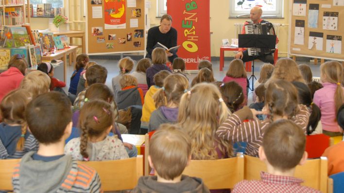 Kinder lauschen der Geschichte, die Schauspieler Joachim Schönfeld liest; mit im Bild Volker Schindel mit dem Akkordeon © rbb/Redaktion OHRENBÄR