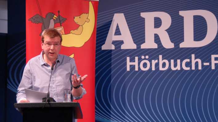 OHRENBÄR-Autor Hubert Schirneck liest am Pult stehend Geschichten © rbb/Redaktion OHRENBÄR OHRENBÄR-Autor Hubert Schirneck liest am Pult stehend Geschichten © rbb/Redaktion OHRENBÄR