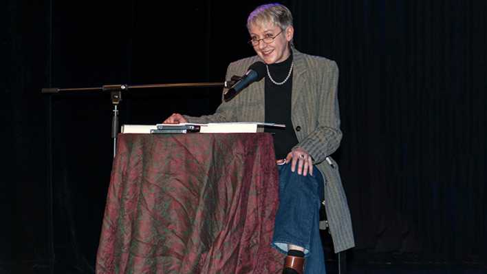Porträt der Autorin Sibylle Nägele bei einer Lesung, sitzend am Tisch vor einem Mikrofon (Quelle: Gerhard Haug)