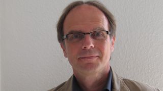 Porträt des Autoren Jürgen Nendza, vor einer hellen Wand (Quelle: privat)