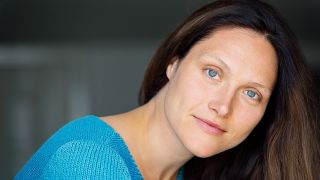 Seitliches Porträt der Schauspielerin Nadine Nollau, vor dunklem Hintergrund, mit blauem Pullover (Quelle: Thomas Leidig)