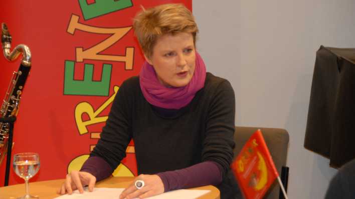 OHRENBÄR-Autorin Stephanie Schneider liest, hinter ihr der rote OHRENBÄR-Banner (Quelle: rbb/OHRENBÄR/Birgit Patzelt)