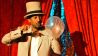 Zauberer Daniel Reinsberg mit einem großen Zylinderhut sticht mit einer langen Nadel in einen weißen Luftballon, der nciht platzt © Thomas Ernst