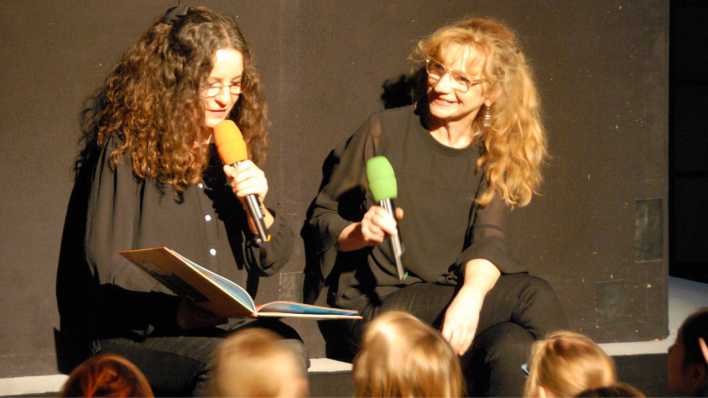 Conni und Nina von der Kindersendung "Zappelduster" auf Antenne Brandenburg, auf der Bühne und mit Mikrofonen in der Hand (Quelle: rbb/OHRENBÄR/Birgit Patzelt)
