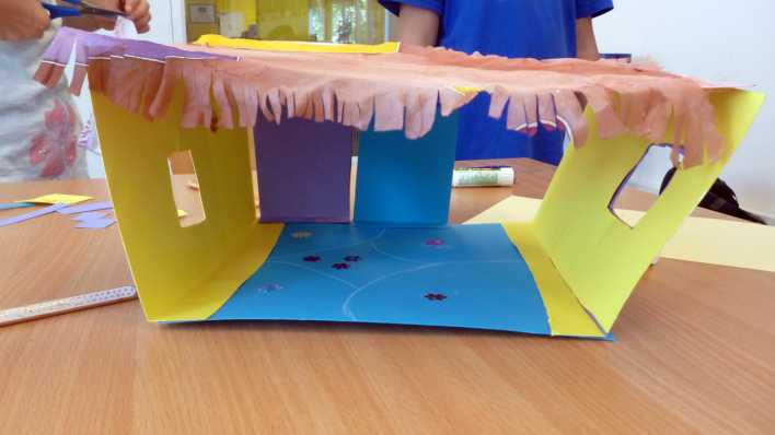 Bunte Bastelei auf einem Tisch, im Hintergrund werkeln Kinder (Quelle: rbb/OHRENBÄR/Clara Herrmann) Bunte Bastelei auf einem Tisch, im Hintergrund werkeln Kinder (Quelle: rbb/OHRENBÄR/Clara Herrmann)