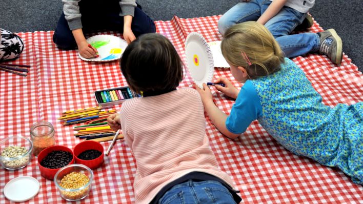 Kinder liegen auf einer rot-weiß karierten Decke und bemalen Pappteller, in Schüsseln verschiedene Hülsenfrüchte (Quelle: rbb/OHRENBÄR/Lisa Thieler)