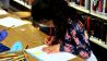 Ein Mädchen sitzt am Tisch und malt, dahinter eine Bücherregal (Quelle: rbb/OHRENBÄR/Lisa Thieler)