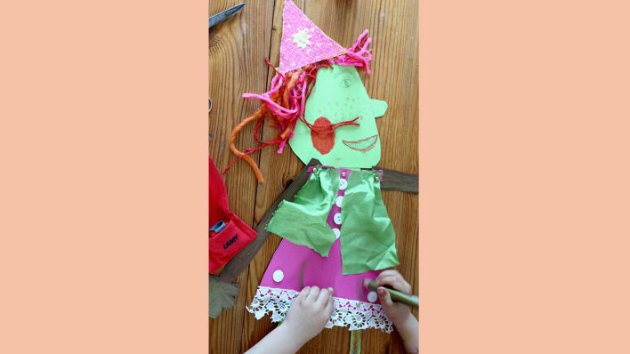 Ein Kind bastelt an einer beweglichen Hexenfigur aus buntem Papier und Stoffen (Quelle: rbb/OHRENBÄR/Martha Zan)