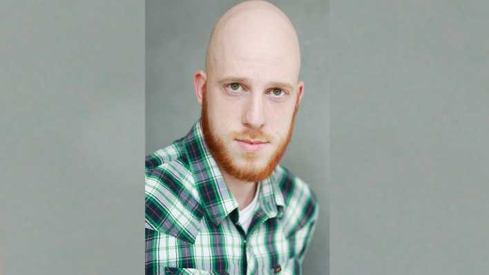 Porträt des Schauspielers Sebastian Witt mit kariertem Hemd, grau-grüner Hintergrund (Quelle: Joachim Gern)