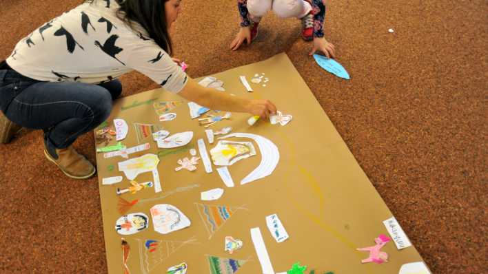 Kinder und Workshopleiterin gestalten ein Plakat (Quelle: rbb/OHRENBÄR/Lisa Thieler)