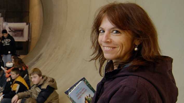 Autorin Sigrid Zeevaert mit Büchern in der Hand vor sitzenden Schülern in einer großen Röhre (Quelle: privat)